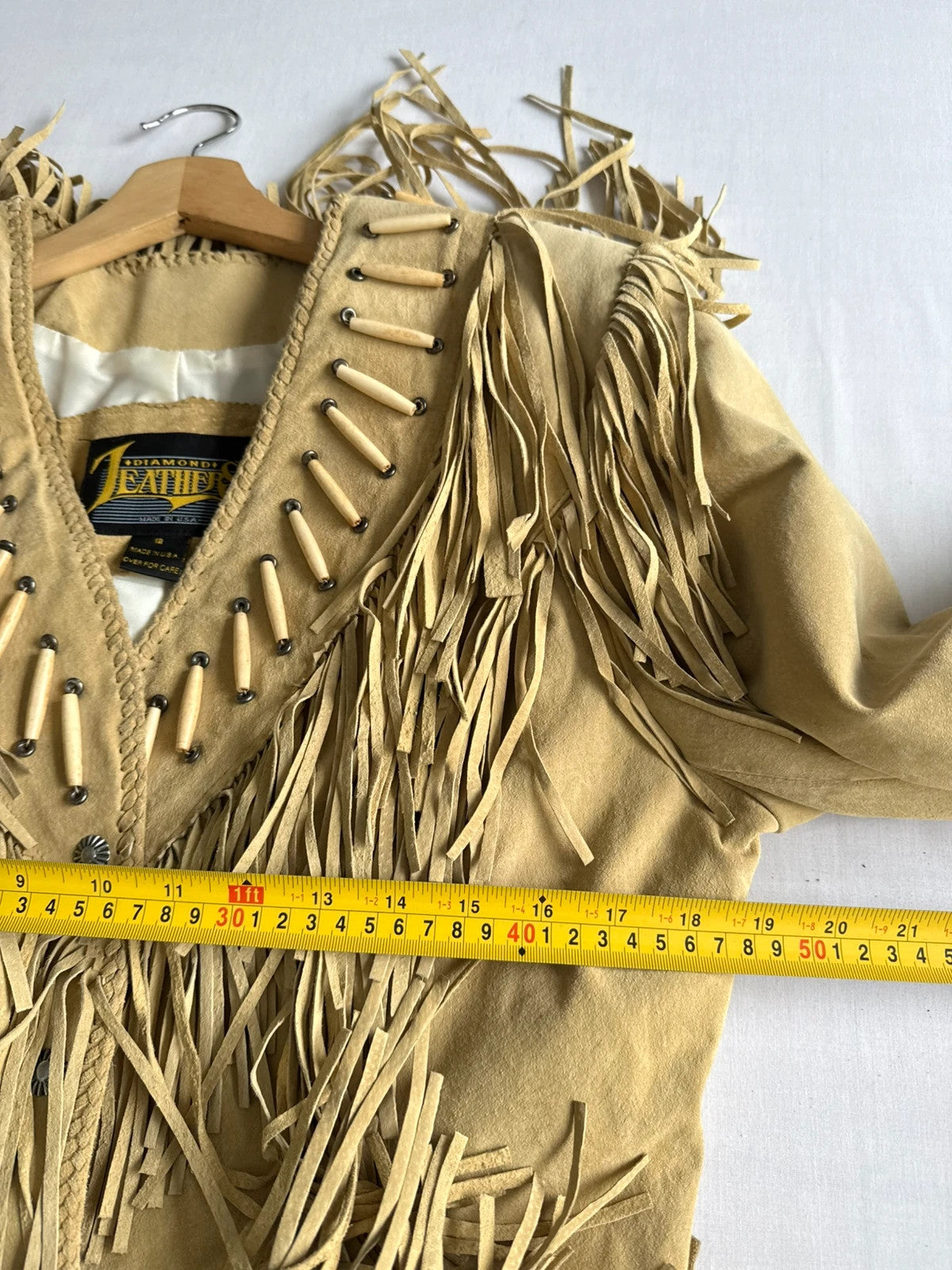 Diamond Leathers tan suede jacket with fringe, beaded arrow detailing, and snap closure.