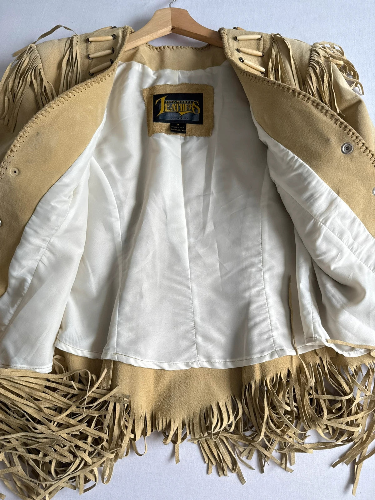 Diamond Leathers tan suede jacket with fringe, beaded arrow detailing, and snap closure.