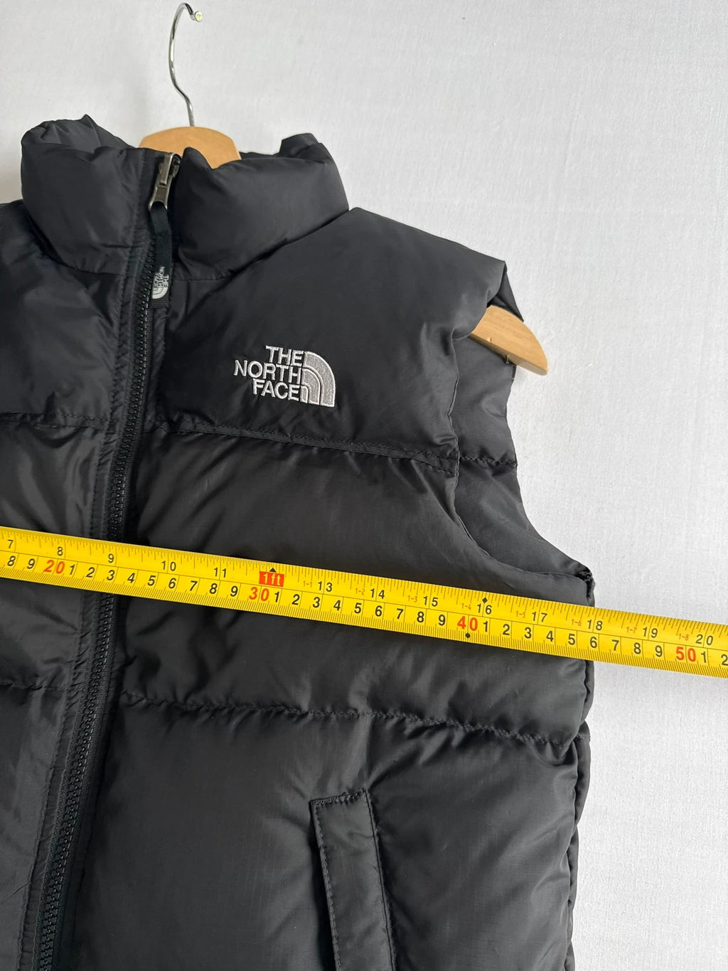 The North Face black puffer gilet with embroidered logo and stand-up collar.