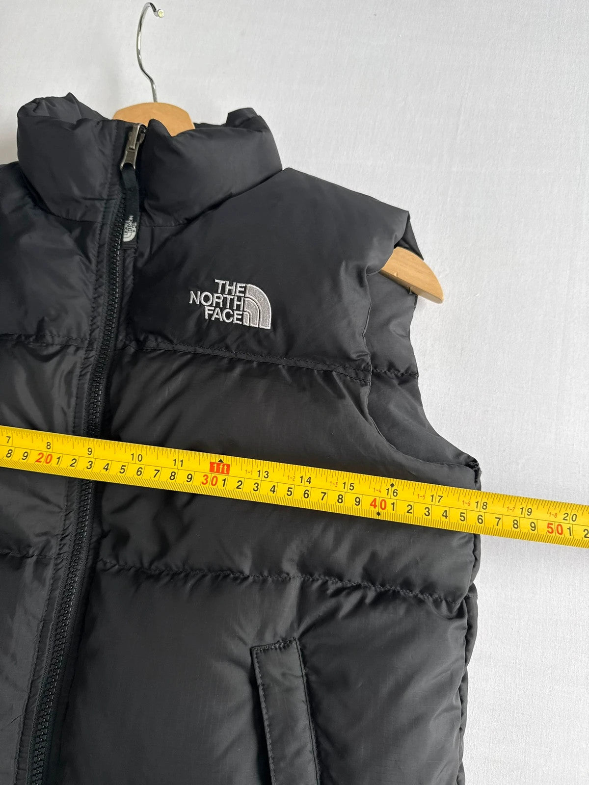 The North Face black puffer gilet with embroidered logo and stand-up collar.
