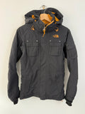 The North Face black ski jacket with tan accents, quilted lining, and multiple pockets.
