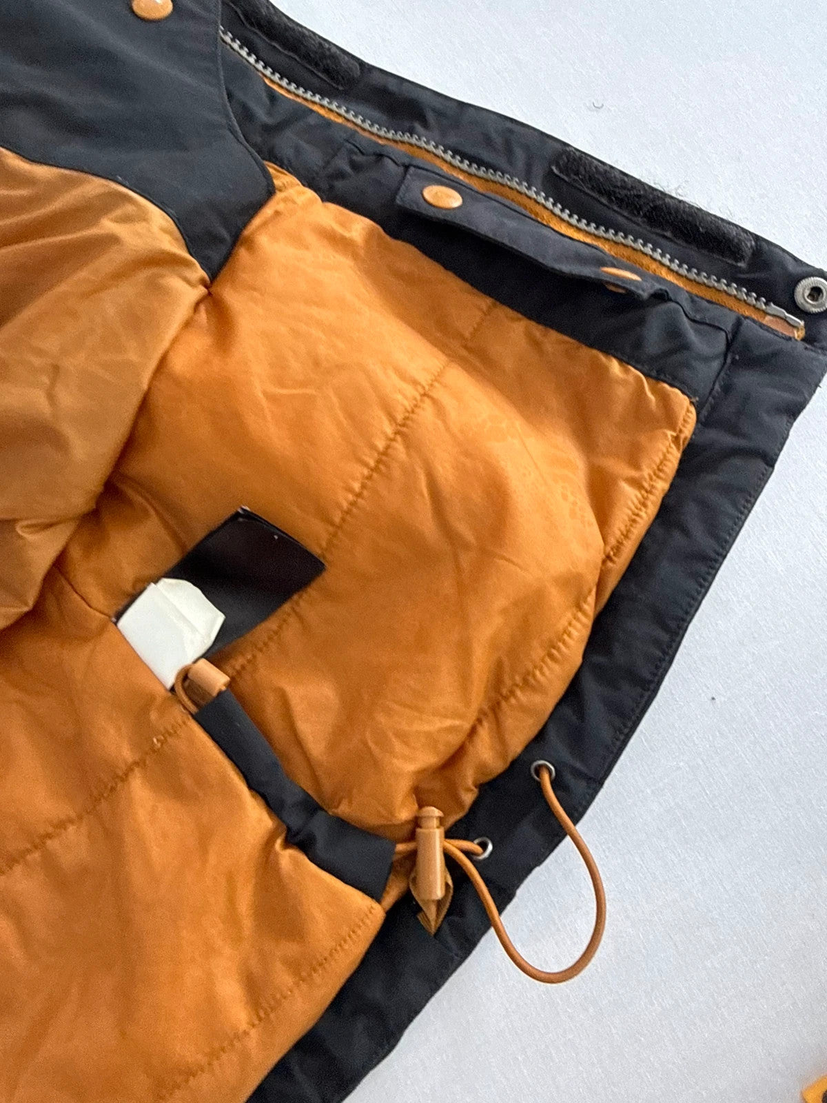 The North Face black ski jacket with tan accents, quilted lining, and multiple pockets.
