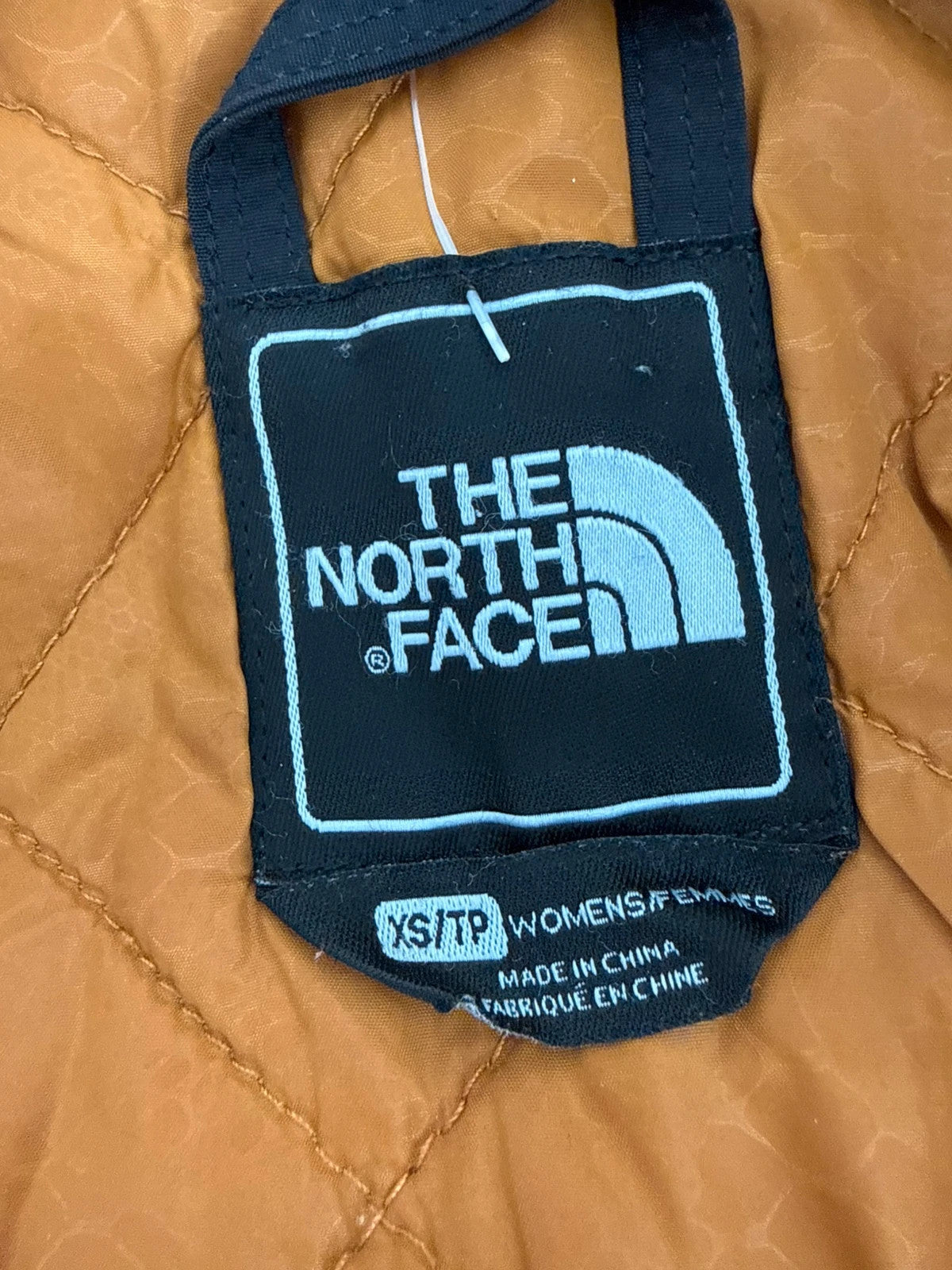 The North Face black ski jacket with tan accents, quilted lining, and multiple pockets.