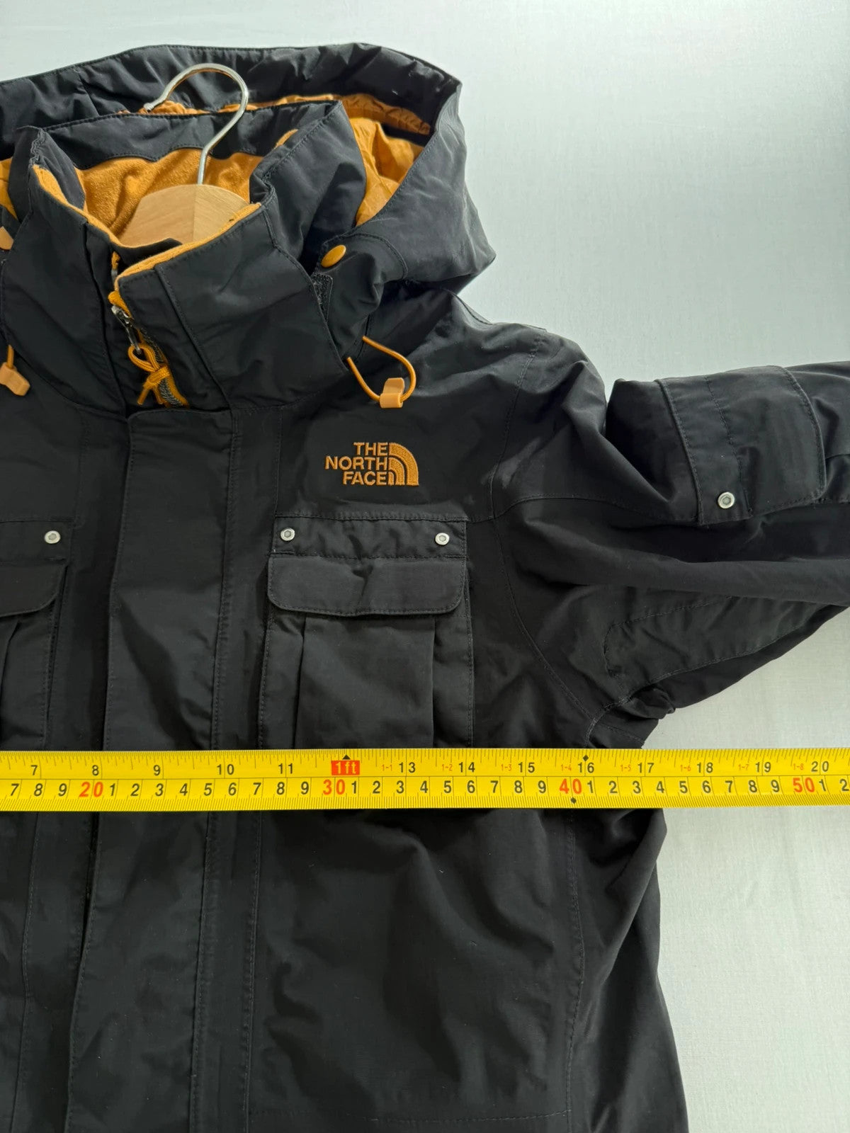 The North Face black ski jacket with tan accents, quilted lining, and multiple pockets.