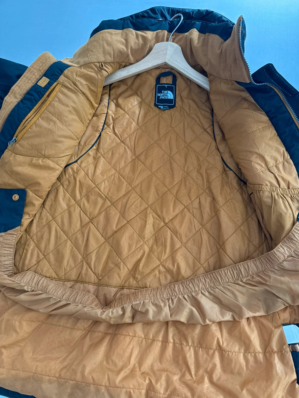 The North Face black ski jacket with tan accents, quilted lining, and multiple pockets.