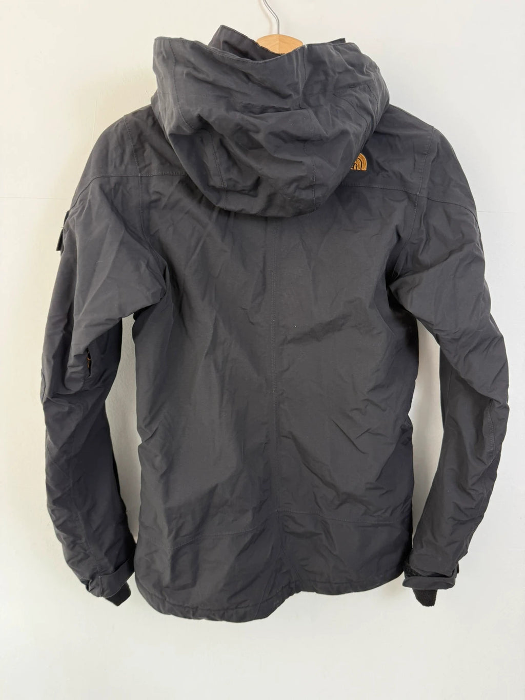 The North Face black ski jacket with tan accents, quilted lining, and multiple pockets.
