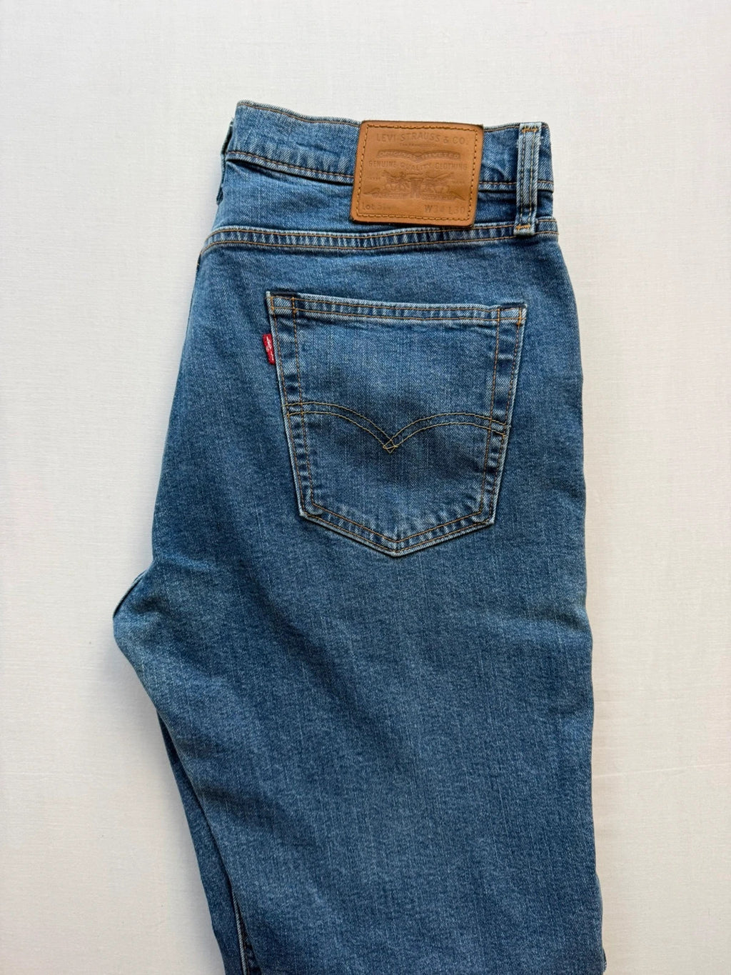 Levi's blue straight jeans with leather back patch and red tab detail.
