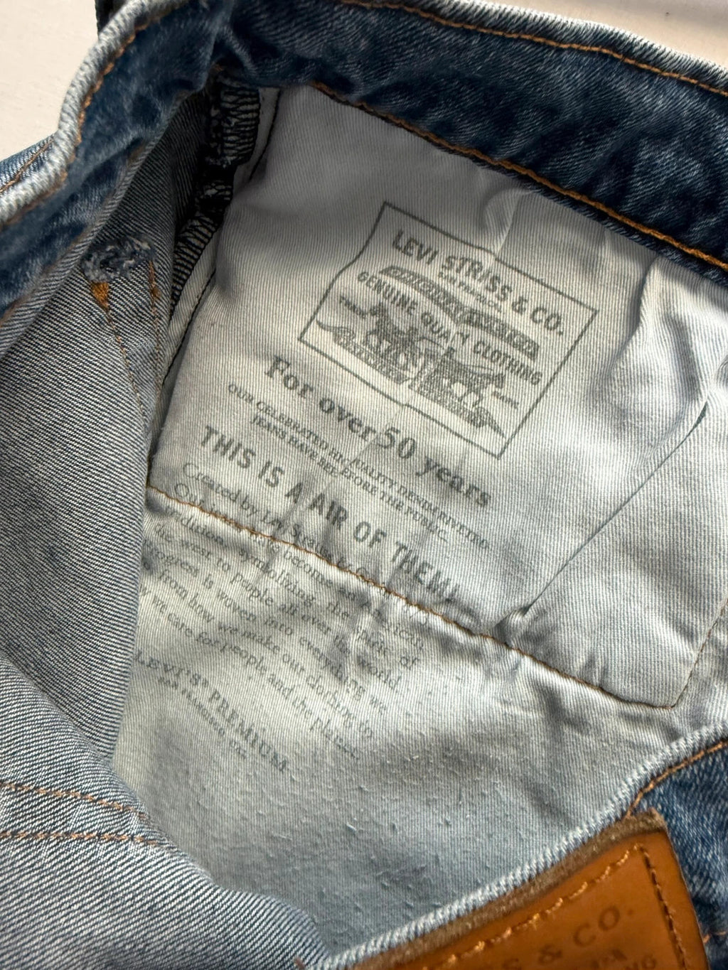 Levi's blue straight jeans with leather back patch and red tab detail.